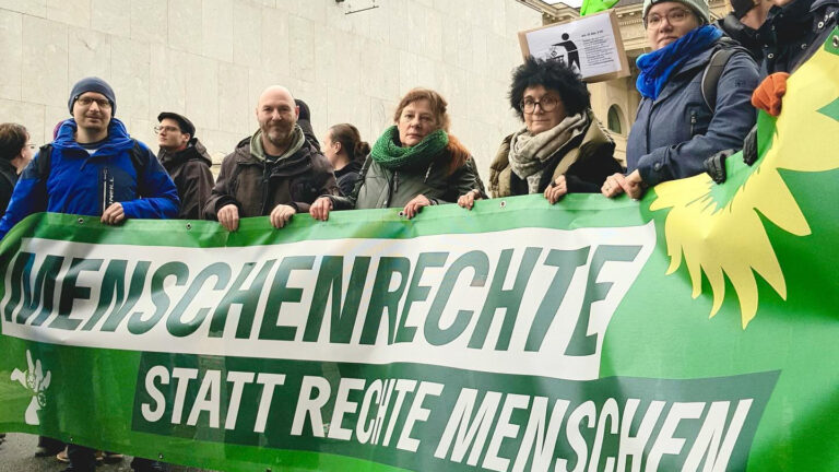 GRÜNE Abgeordnete halten Transparent mit der Aufschrift "Menschenrechte statt rechte Menschen" hoch.