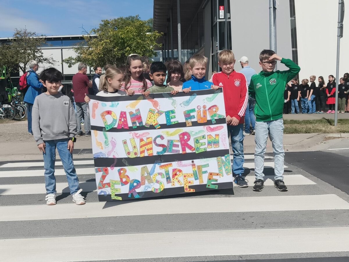 Kinder mit einem Schild "Danke für unseren Zebrastreifen"